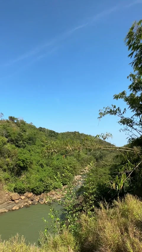 Man Observing Waterfall and Lush Valley, Green Mountains, Sunny Vertical Shot Stock Footage 324770412