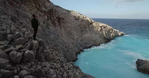 Man on Ocean Cliff Greece Drone Shot Stock Footage 106340289
