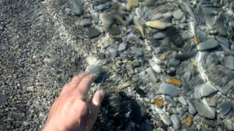 Man on the ocean holds in his hand a pebble Stock Footage