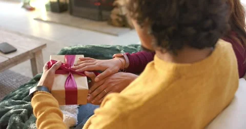 Man offering gold gift box as couple are opening red ribbon on blanket-covered Stock Footage 343098244