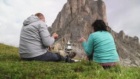 Man offering tea to woman while camping in the Dolomites with scenic mountain Stockbeeldmateriaal 319599953
