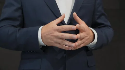 Man in office building in blue jacket explains shows with hand gestures on stage Stock Footage 134813214