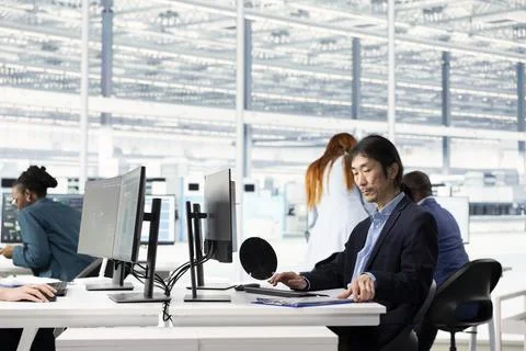 Man in office configuring PCB electronic hardware setups using computer 写真素材