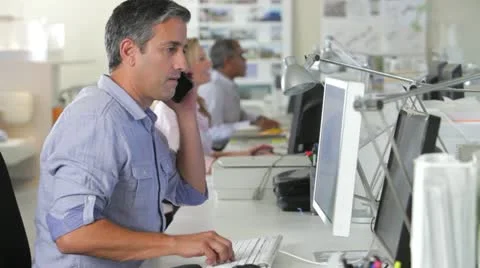 Man Office At Desk Using Mobile Phone And Computer Stock Footage