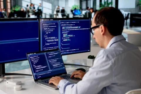 Man In Office Focused On Coding New Web Project Using Laptop Computer. 写真素材