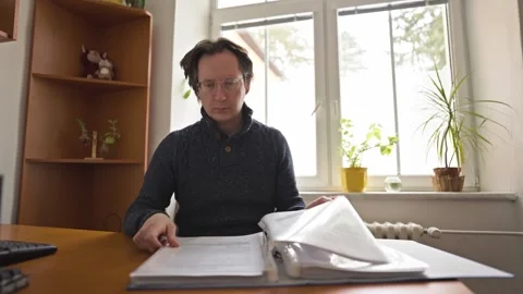 A man in an office leafs through a large file folder containing documents Video stock 330911402