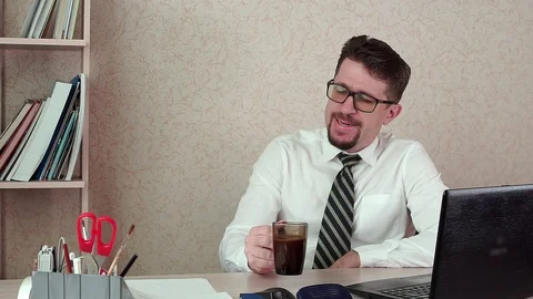 Man office Manager with a beard and glasses, drinking coffee for a laptop Stock-Footage 100394890