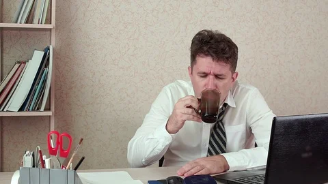 Man office Manager sleepy drinks coffee at work. Video stock 100399409
