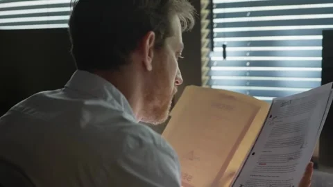 Man in an office opening a secret folder and scanning its contents Stock Footage 305536210