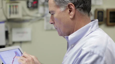 Man in office reviews charted data on electronic tablet pc. Stock Footage 30135620