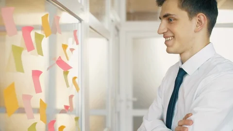 Man in office use sticky notes on glass for idea creation or solve problem at hi Vidéo 119353313