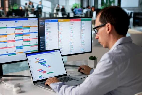 Man In Office Uses Computer Software To Organize Business Schedule Tasks. Fotos de archivo