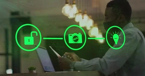 Man in office using laptop with digital security icons overlaying screen Stock Photos