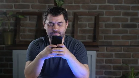 Man in office at a workplace and writing a message on a smartphone. 스톡 동영상 128095258