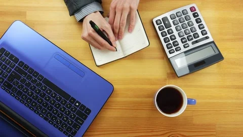 A man in the office writes tasks for the day in the diary on a wooden table Stock Footage 101839975