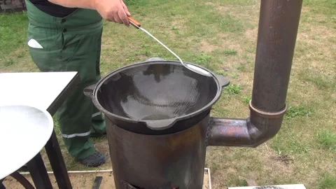 A man oils a hot grill. Brazier on an open fire Stock Footage 279803282