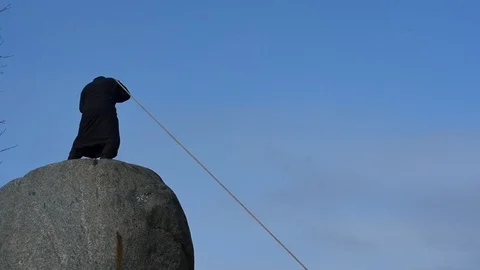 Man in old ancient cloth pullig rope on the top of rock Stock Footage 103691135