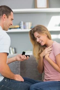 Man on one knee proposing to shocked girlfriend Stock Photos