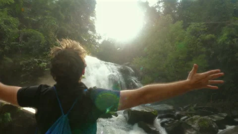 Man with open arms in front of waterfall, enjoying serenity of nature Stock-Footage 284148444