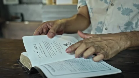 Man open the book of the bible and read it on a wooden table Stock Footage 288413764
