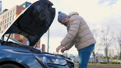 A man open the hood is seen working on a broken Stock Footage 234137341