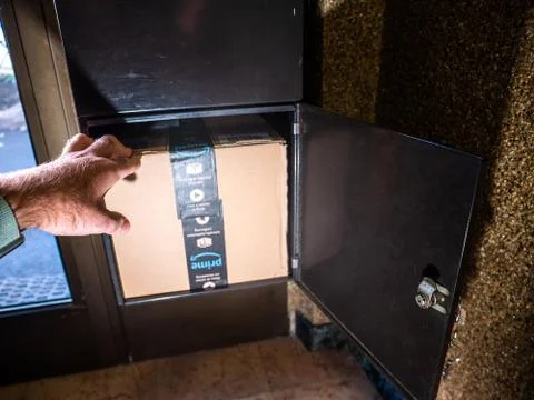 Man open mailbox discovering inside big Amazon Prime Cardboard Stock Photos