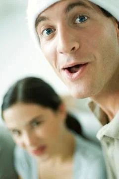 Man with open mouth looking at camera, woman smiling at camera in background Stock Photos