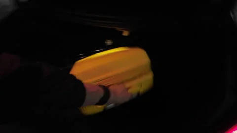 Man open trunk of luxury black sedan car and takes out yellow suitcase. Vidéo 235385014