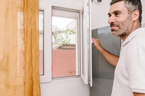 Man Open Window for Fresh Air And Cool Home In Summer Heat, house burping tre Stock Photos