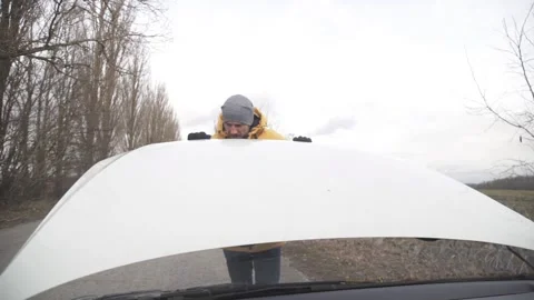 A man opened the hood of a car, trying to figure out what the problem was. Stock Footage 264094640