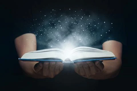 Man opened a magic book with growing lights and magic powder. Learning and .. Stock Photos