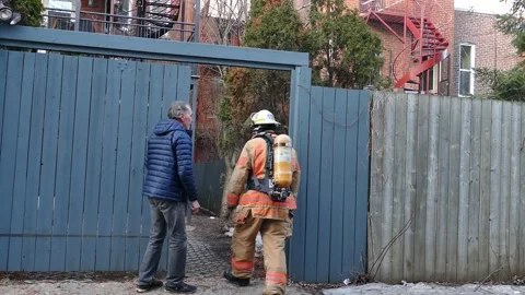 Man opening backyard door to firefghter Stock Footage 138530717