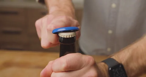Man opening beer bottle with a blue bottle opener Stock Footage 247784189