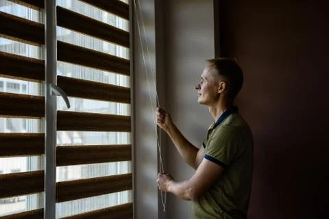 The man is opening  the blinds. Stock Photos