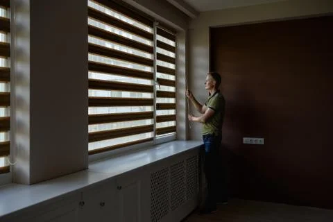 The man is opening  the blinds. Stock Photos