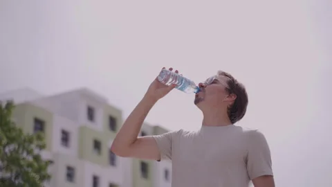Man opening a bottle of water in hot weather Stock Footage 293277211