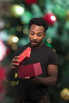Man opening box looking inside christmas gift surprise excited expression wit Stock Photos