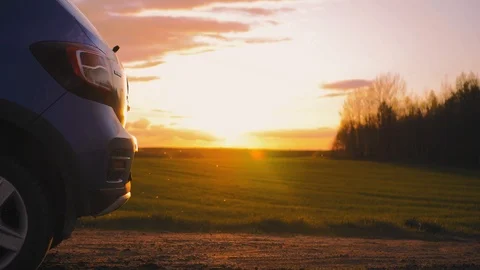 Man is opening car trunk, sits on it and is uses his smartphone. Car in the Stock Footage 95323975