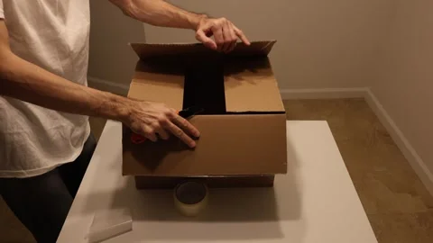 Man opening cardboard parcel with utility knife Stock Footage 327067299