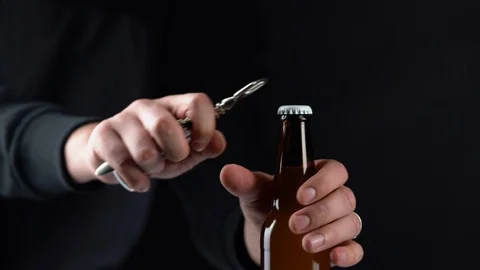 Man opening cold bottle of beer with cap on black background. Hands cracking Stock Footage 123369375