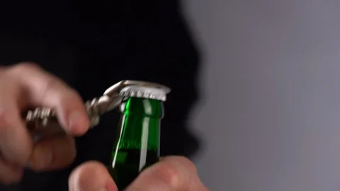 Man opening cold bottle of beer with cap on black background. Hands cracking Stock Footage 123373209