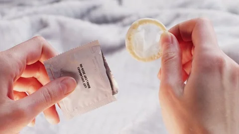 Man opening condom, close up, Hand holding a condom in package, close up on Stock Footage 233634495