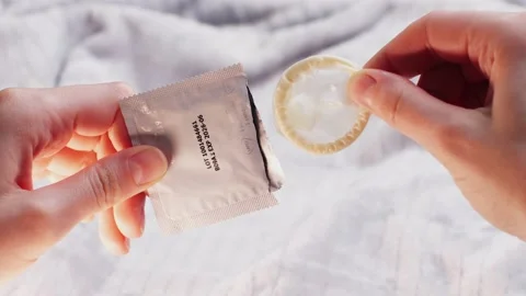Man opening condom, close up, Hand holding a condom in package, close up on Stock Footage 236479149