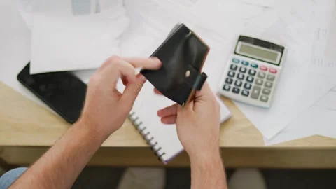 Man opening an empty wallet near unpaid bills and calculator. Concept of financi Stock Footage 341880823
