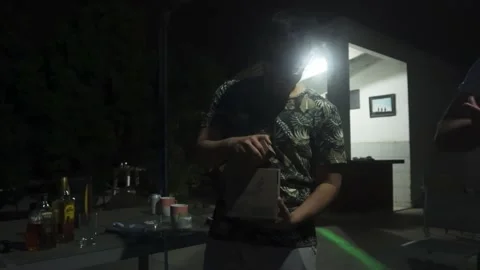 A man opening a gift from his friends for his birthday of drinks in skull-shaped Stock Footage 170020173