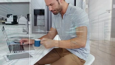 Man opening laptop and starting tech work at kitchen island, sipping blue mug, Stock Footage 333803458