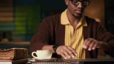 Man Opening Laptop at Table with Old Book and Cup of Coffee Indoors Stock Footage 302519806
