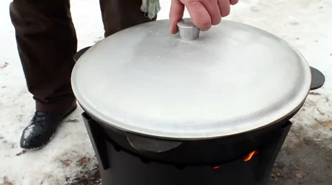 The man opening the lid and checking the pieces of mutton in a cauldron. Stock Footage 63660889