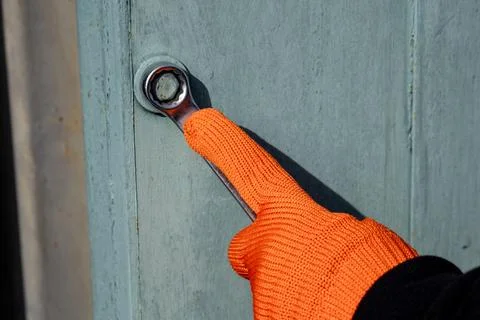 A man is opening a nut with a wrench, using careful grip while wearing an o.. Stock Photos
