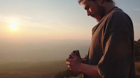 Man opening an old tin box on the edge of a mountain overlooking endless field Stock Footage 121803560